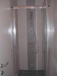 a shower in a bathroom with a glass door at Azúr Ház Viola Apartman in Sárvár