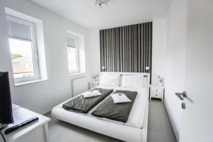 a white bedroom with a bed and a desk at Azúr Ház Viola Apartman in Sárvár