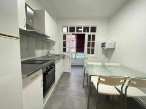 uma cozinha com um balcão, uma mesa e cadeiras em O cuarto de abastos em Ourense