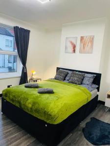 a bedroom with a green bed with a window at Newly refurbished city house with Hot Tub in Lincoln