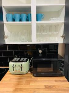 a kitchen with a microwave and blue cups in cabinets at Central area terraced house with private hot tub in Lincoln