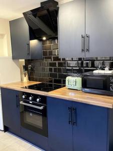 a kitchen with blue cabinets and a stove top oven at Newly refurbished city house with Hot Tub in Lincoln