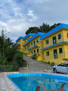 a yellow and blue apartment building with a swimming pool at Residencial Sítio Paraíso in Itacaré