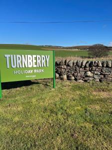 un letrero para auryery camping resort junto a una pared de piedra en Turnberry Holiday Home en Turnberry