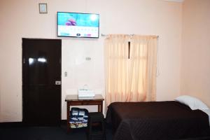 a bedroom with a bed and a tv on the wall at Hotel Realidad in Guatemala