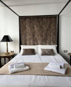 a bedroom with a large white bed with two towels on it at Alèa Rooms in Lecce