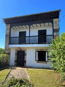 Casa blanca con balcón en la parte superior. en Estupenda Casona Rural Montañesa, en Trasvia