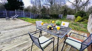 a table and chairs on a wooden deck with orange juice at E2M Stays Beautiful House Close To Heathrow Airport- Walking Distance To Thames River in Egham