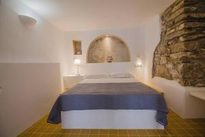 a bedroom with a bed and a stone wall at Παραδοσιακό κυκλαδίτικο στούντιο in Ios Chora