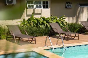 a couple of chairs sitting next to a swimming pool at Arco Iris Chalés I in Maresias