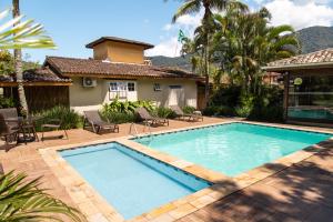 a swimming pool in the backyard of a house at Arco Iris Chalés I in Maresias