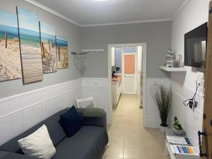 ein Wohnzimmer mit einem blauen Sofa und einem TV in der Unterkunft Casa del Mar a la Sierra in Setenil de las Bodegas