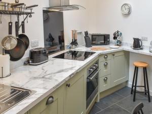 uma cozinha com bancadas de mármore branco e electrodomésticos em Ugly Duckling Cottage em Broughton in Furness