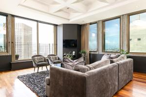 a living room with a large couch and windows at #1701 Cartwright - Dark Glamour in Cape Town