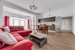 a living room with a red couch and a kitchen at ARI Central Grand Apartments - Luxurious Stay in Arad