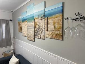 a wall with four paintings of a beach and the ocean at Casa del Mar a la Sierra in Setenil