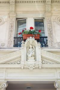 a building with a statue on a balcony with red flowers at Hotel Meslay Republique in Paris