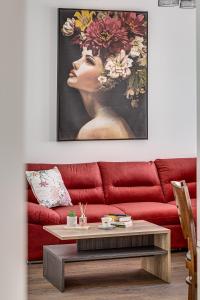 a living room with a red couch with a painting of a woman at ARI Central Grand Apartment in Arad