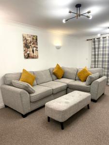 a living room with a gray couch and yellow pillows at Angel view - 4 bed property- perfect for contractors & families in Milton Keynes