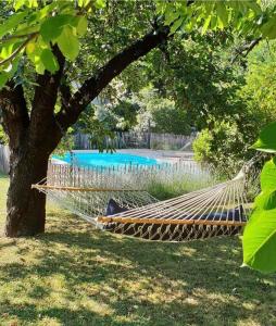uma rede pendurada numa árvore junto a uma piscina em La Cerisaie - Chambres d'hôtes & gites em Riols