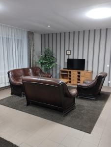 a living room with two leather couches and a television at Vila 1936 in Šiauliai