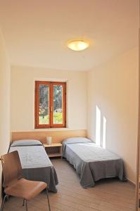 a bedroom with two beds and a chair and a window at Appartamenti Casa Pineta in Marina di Campo