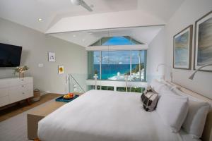 um quarto com uma grande cama branca e uma grande janela em Azura Bermuda em Bermuda