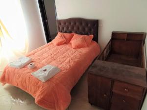 a bed with an orange comforter and two towels at Villa Alioc in Iza