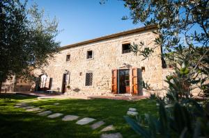 a stone building with a grass yard in front of it at Agriturismo Borgo tra gli Olivi in Castiglion Fiorentino