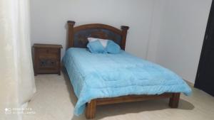 a bed with a blue blanket and a night stand at Villa Alioc in Iza