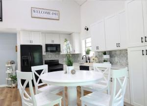 cocina blanca con mesa blanca y sillas blancas en Cottage in the woods at Emerald Lakes Estate en Saint Augustine