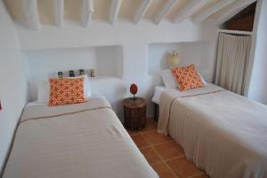 2 bedden in een kamer met witte muren en oranje kussens bij Casa Miguel Montefrio in Granada