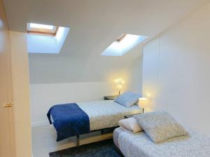 um quarto com 2 camas e uma clarabóia em Elegante Ático Encamp - FREE Parking Wifi SmartTv - Con altillo y 2 baños completos! em Encamp