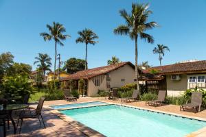 a villa with a swimming pool and palm trees at Arco Iris Chalés I in Maresias
