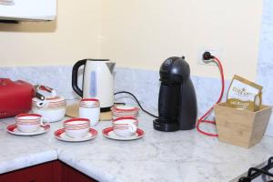 un comptoir avec une bande de tasses à café dessus dans l'établissement Dimora Puccini, à Lucques