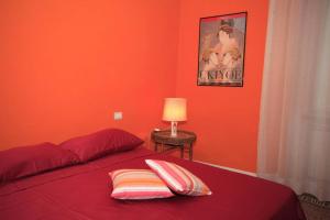 - une chambre avec des murs orange et un lit avec deux oreillers dans l'établissement Dimora Puccini, à Lucques