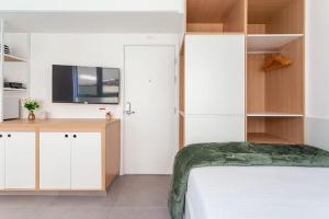 a bedroom with a bed and a tv on a wall at Studio Harmonia, Moderno, Aconchegante e com Garagem in Sao Paulo +19 photos