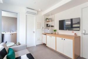 a living room with a kitchen with a tv on the wall at Studio Harmonia, Moderno, Aconchegante e com Garagem in Sao Paulo