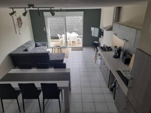 eine Küche und ein Wohnzimmer mit einem Sofa und Stühlen in der Unterkunft Maison de 100M2 avec terrasse in Wardrecques