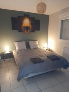 ein Schlafzimmer mit einem großen Bett mit zwei Leuchten in der Unterkunft Maison de 100M2 avec terrasse in Wardrecques