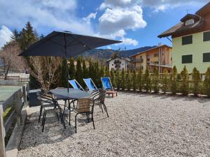 a table with chairs and an umbrella on a patio at Suite a Folgaria in Folgaria