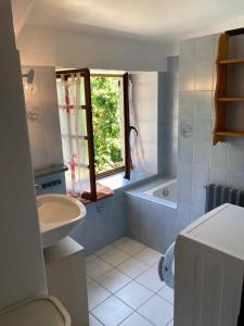baño con lavabo, bañera y ventana en Gîte L'hirondelle, en Meyrueis