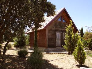 een klein houten huis in een tuin met bomen bij El Muerdago de Cañada in Cañada del Hoyo