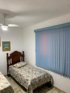 a bedroom with two beds and a window with blue blinds at Cantinho de Maria in Aparecida