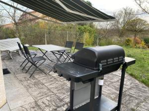 a grill on a patio with a table and chairs at Maison PHILIPPE et Fils in Saint-Bonnet-près-Riom