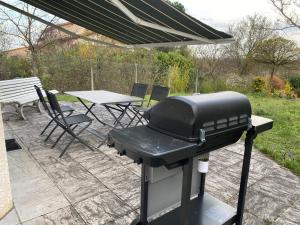grill na patio ze stołem i krzesłami w obiekcie Maison PHILIPPE et Fils w mieście Saint-Bonnet-près-Riom