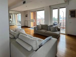 uma sala de estar com 2 sofás e uma sala de estar com janelas em Penthouse Suite - Skyline view em Busto Arsizio