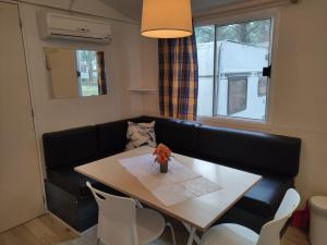 een woonkamer met een tafel en een zwarte bank bij Mipro Mobilhome 5 in Lido di Spina