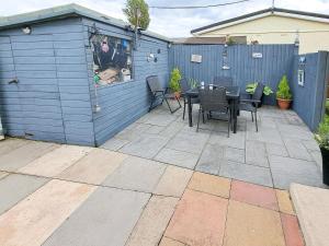 a blue shed with a table and chairs on a patio at Beach Tonic in Humberston