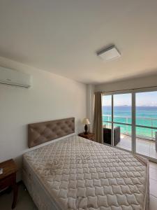 Schlafzimmer mit einem Bett und Meerblick in der Unterkunft AP ESPETACULAR VISTA MAR PRAINHA EM ARRAIAL DO CABO in Arraial do Cabo